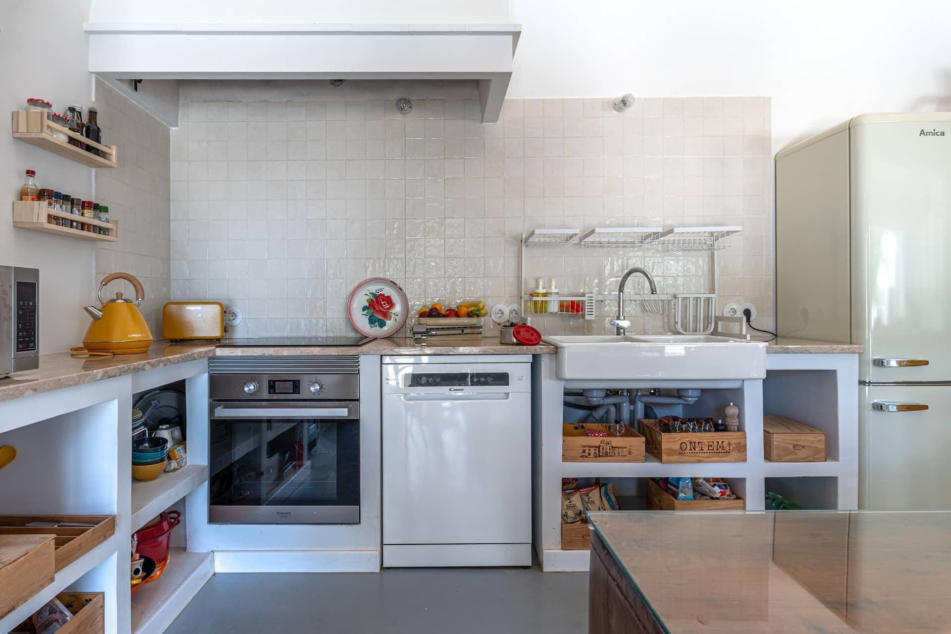 Eine moderne Küche mit weißen Schränken, einem eingebauten Ofen, einer Spülmaschine und einem Kühlschrank.