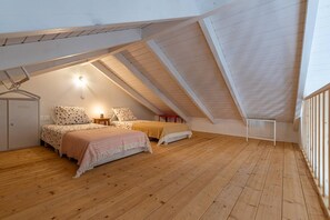 A bedroom with two beds, a wardrobe, and a small table with a lamp.