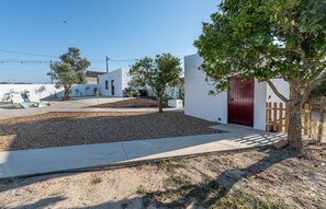 Bairro residencial com casas brancas, uma porta vermelha e uma árvore.