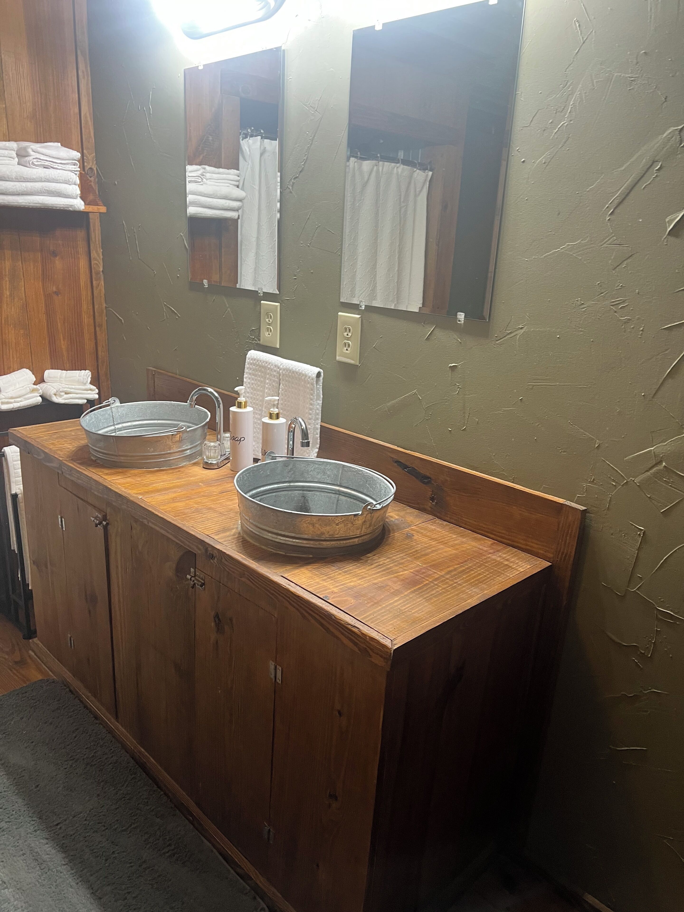 Une coiffeuse en bois avec un lavabo rond, un miroir et un porte-serviettes.