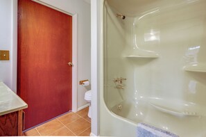 Ein Badezimmer mit Badewanne, Toilette und einer Holztür.