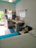 A compact room with a kitchenette, a bed, and a view of the outdoors.