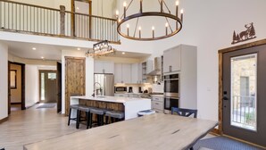 A spacious kitchen with a central island, a dining area with a large table, and a staircase leading to an upper level. - Hot Tub, Pool Table & Fireplace: 5 Mi to Breck! (Blue River)