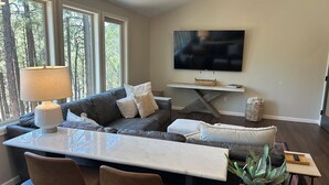 Una sala de estar moderna con un sofá, una mesa de centro, un televisor y un ventilador de techo.