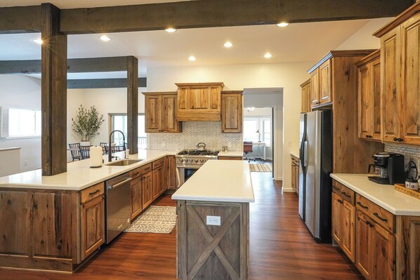 A spacious kitchen with wooden cabinets, a central island, and a large refrigerator.