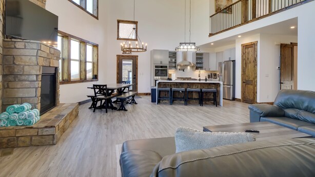 A spacious living area with a stone fireplace, a dining table, and a large sofa. - Luxe Ski Escape! Breck Home w/ Hot Tub & Game Room (Blue River)