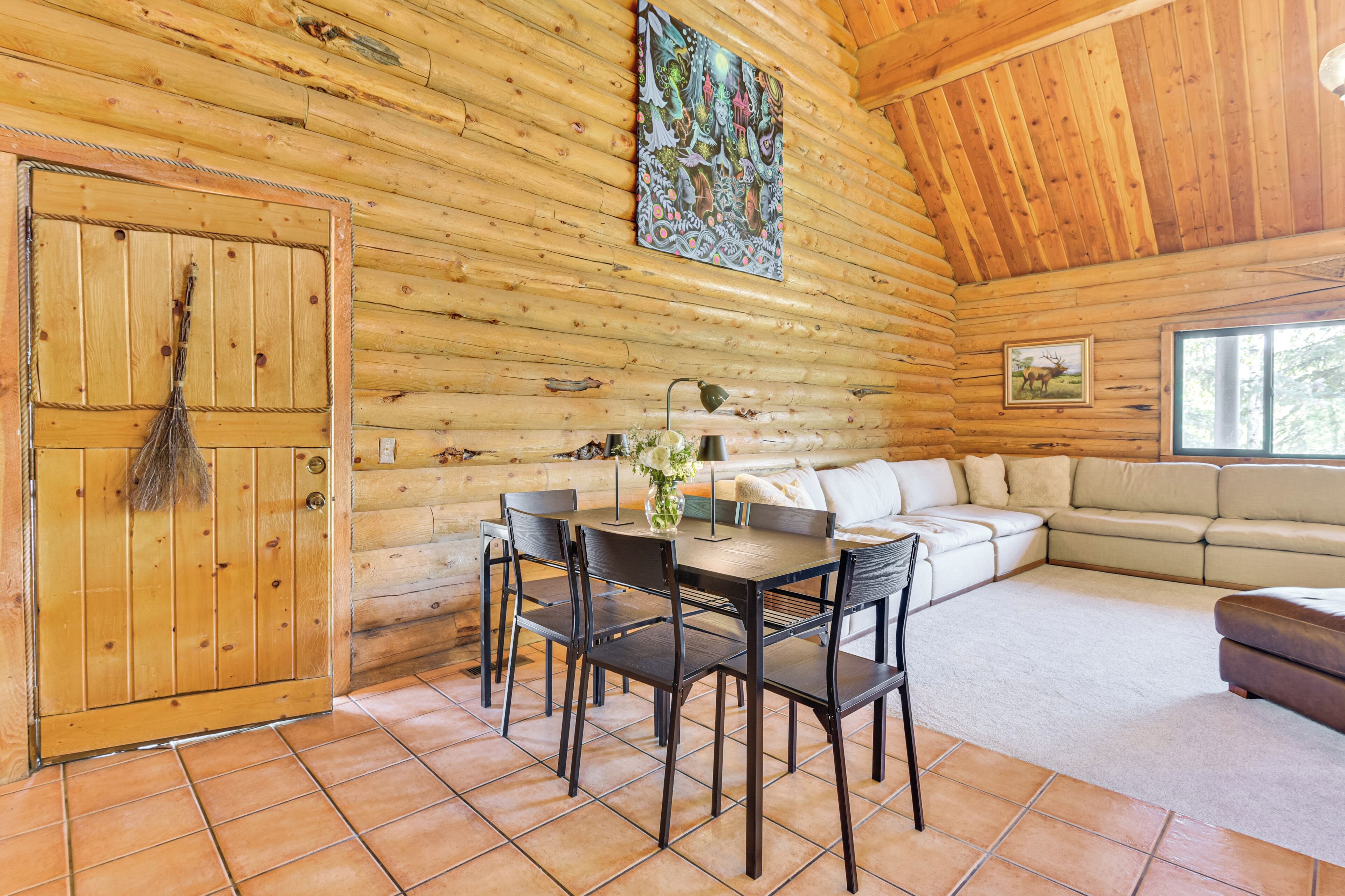 A log cabin interior with a dining area, sofa, and a painting on the wall.