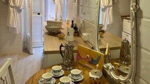 A dining area with a wooden table set for tea, a large ornate mirror, and a view into the adjacent room.