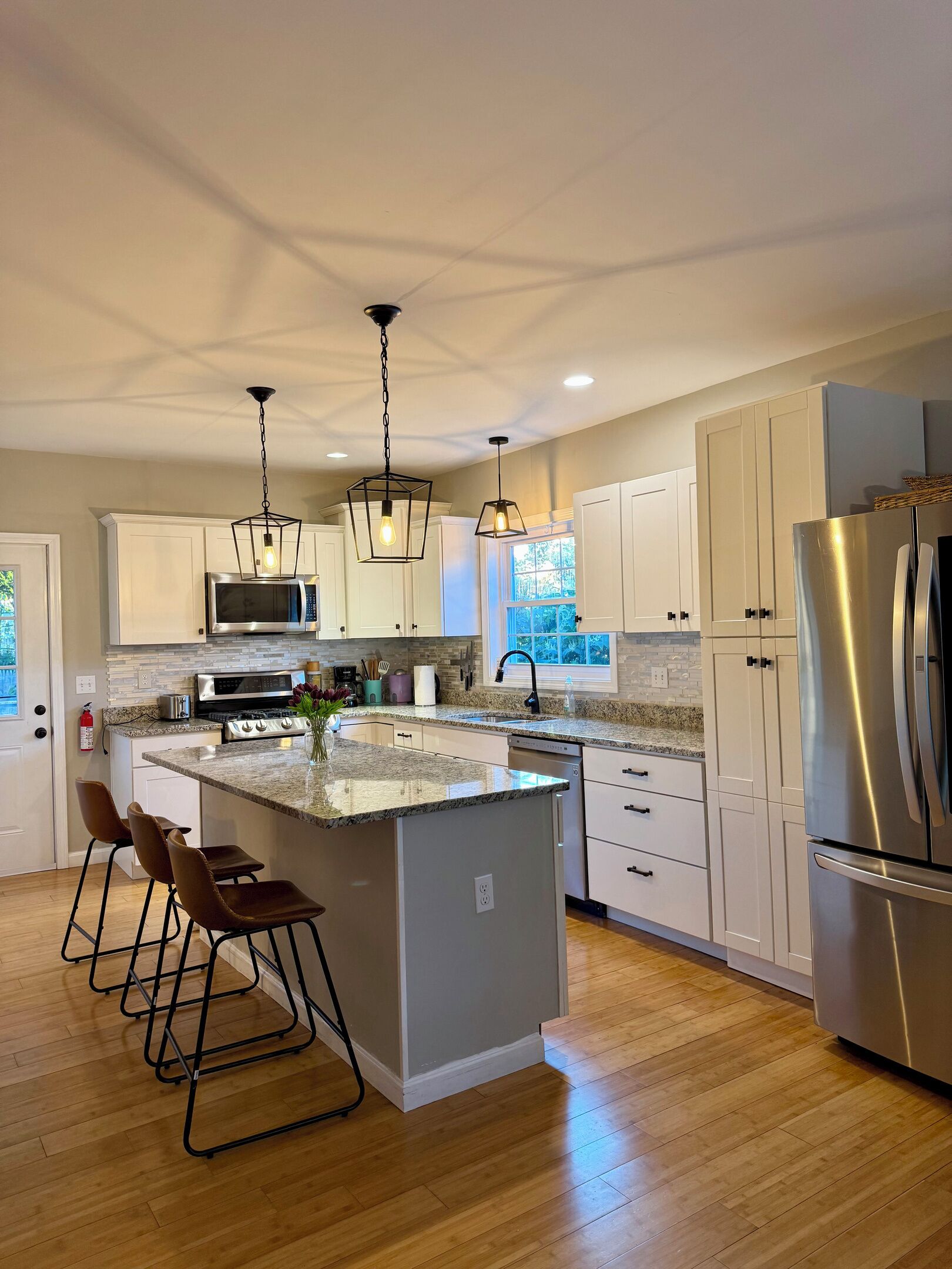 A modern kitchen with a central island, stainless steel appliances, and pendant lighting.