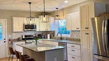 A modern kitchen with a central island, stainless steel appliances, and pendant lighting.