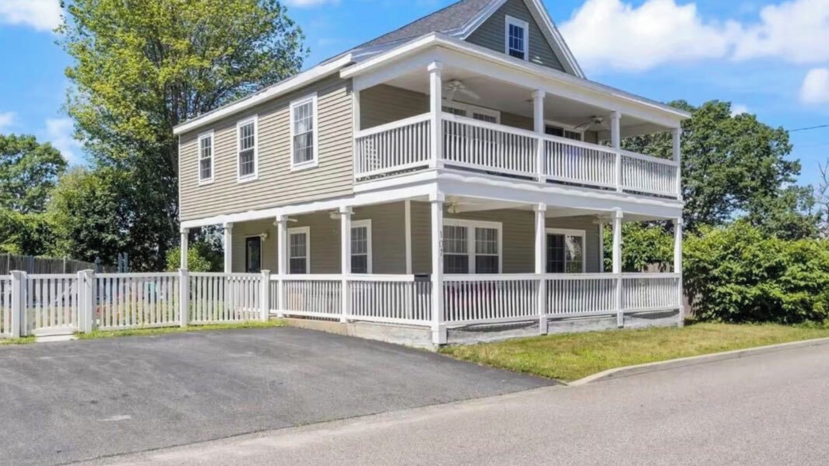 A two-story house with a balcony, a front porch, and a fenced yard.