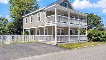 A two-story house with a balcony, a front porch, and a fenced yard.