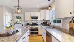 A modern kitchen with white cabinetry, granite countertops, a built-in oven, and a stainless steel range.