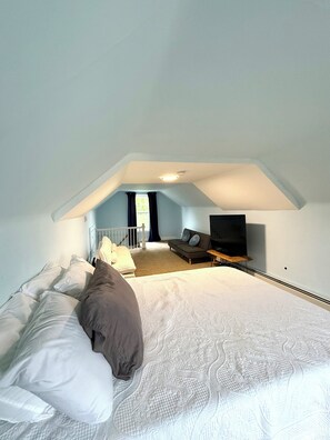 A bedroom with a bed, a television, and a window.