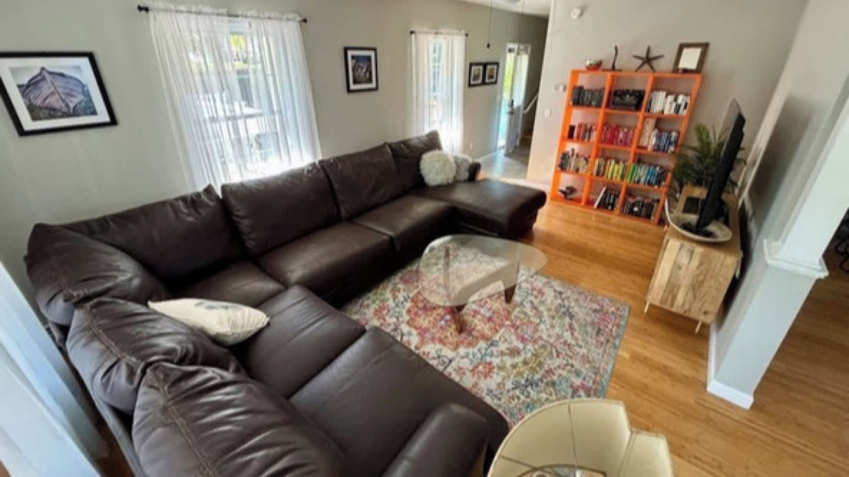 A living room with a brown leather sofa, a coffee table, and a bookshelf.