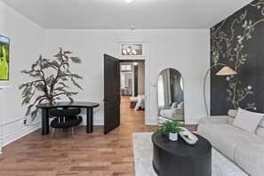 A modern living room with a wooden floor, a black dining table, a grey sofa, and a black armchair. - Tranquil Soulard Haven with Backyard (St. Louis)