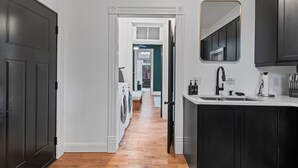 Un couloir avec un coin buanderie, un évier et un miroir.