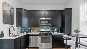 Une cuisine moderne avec des meubles de couleur sombre, des appareils en acier inoxydable, un four à micro-ondes et une cuisinière.