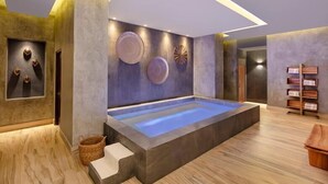 Un cuarto de spa con una bañera grande, placas decorativas en la pared y un estante de madera con toallas.