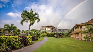 Ein Hotel mit üppigem Garten, Palmen und einem Regenbogen.