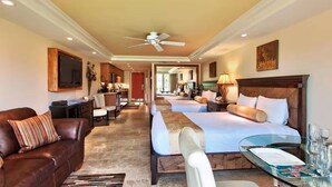 Ein Hotelzimmer mit Sofa, zwei Betten, einer Essecke und einem Fernseher.