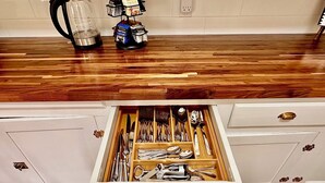Una cocina con mostrador de madera, una cafetera y un estante para especias.