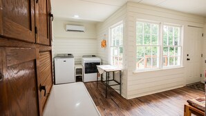 Una cocina compacta con armarios de madera, un refrigerador, una lavadora y una mesa con mantel de encaje.