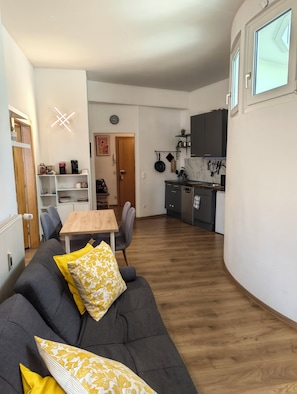 A modern living room with a sofa, a dining table, and chairs. There is a kitchen area with cabinets and a countertop. - Stay at the heart of Villach, great outdoor space (Villach)