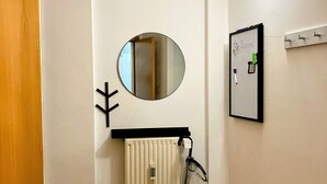 Una habitación con un radiador, un espejo y una lámpara fijada a la pared.