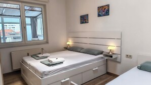 Un dormitorio moderno con dos camas, una ventana y obras de arte en la pared.