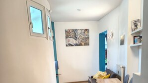 Un interior moderno con una zona de comedor que incluye una mesa y sillas de madera, un cuadro en la pared y una pared azul de acento.