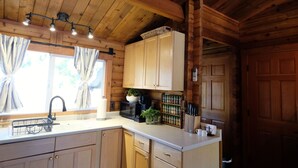 Cocina de cabaña de madera con un lavabo, armarios, microondas y cafetera.