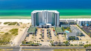 A high-rise hotel with a central courtyard parking area, a beach view, and a clear blue ocean. - It Doesnt Get Any Better Than This! 2BR 2BA Sleeps 8 Beachfront! (Panama City Beach)