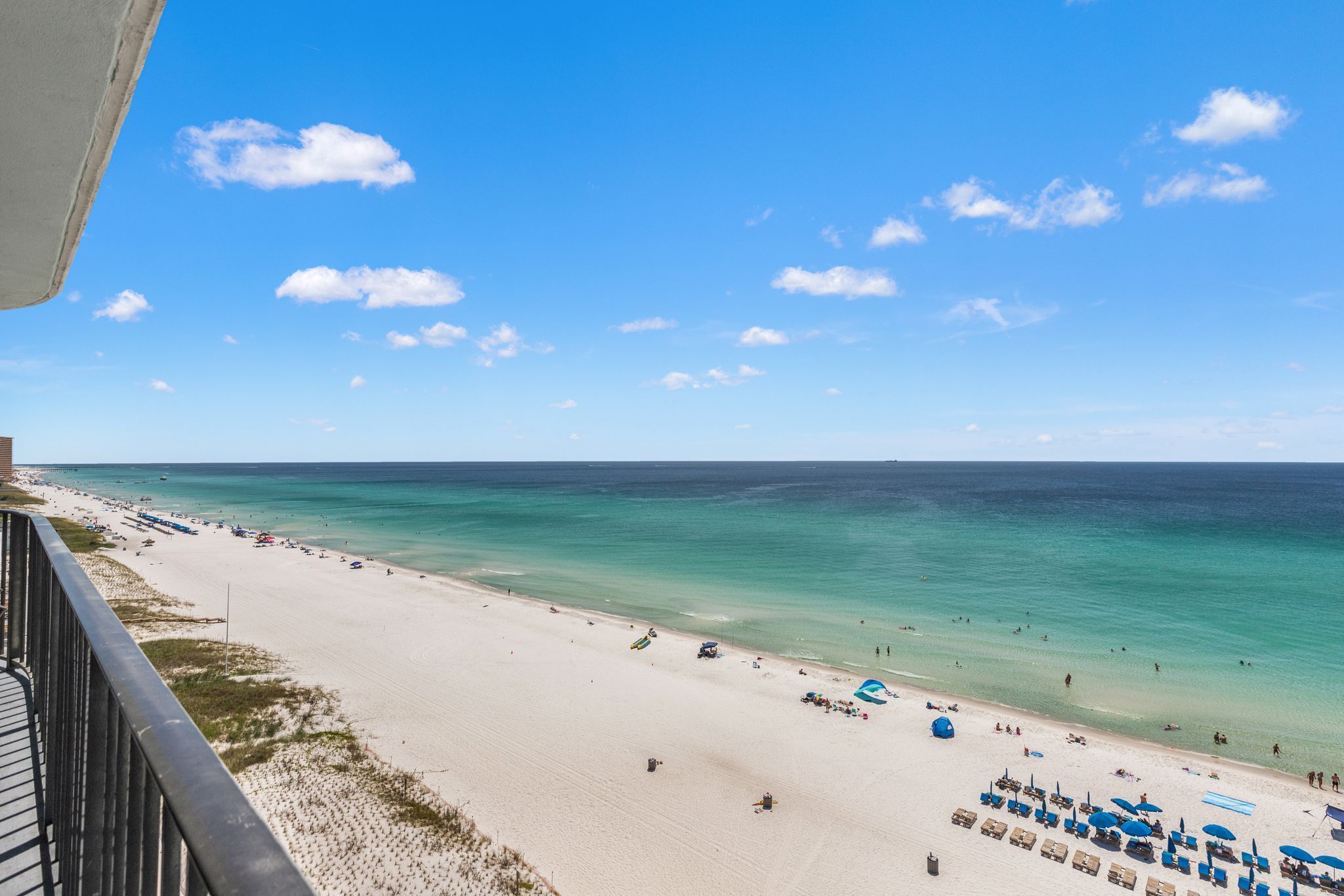A beach with clear turquoise water, a sandy shore, and a few umbrellas and lounge chairs.