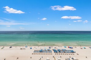 A beach with clear turquoise water, a sandy shore, and several blue umbrellas and sun loungers. - It Doesnt Get Any Better Than This! 2BR 2BA Sleeps 8 Beachfront! (Panama City Beach)