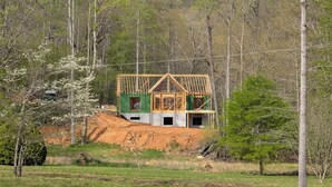 A house under construction surrounded by trees and a grassy field. - Pet-Friendly Luxury Home w/ Hot Tub and Mountain Views (Franklin)