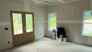 A large, unfinished room with a high ceiling, two doors, and a window. - Pet-Friendly Luxury Home w/ Hot Tub and Mountain Views (Franklin)