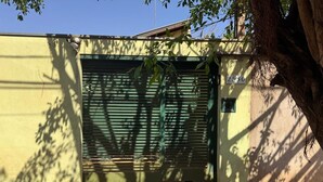 A closed garage door with a house number 2530, a tree casting shadows on the wall, and a concrete ground. - ACCOMMODATION BARRETOS PEÃO FESTIVAL - 2025 (América Barretos)