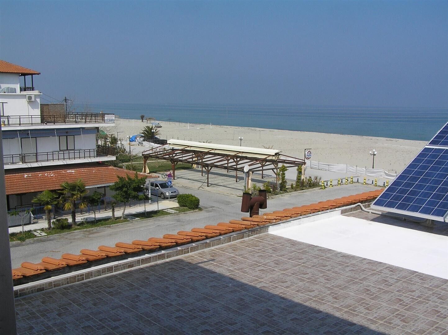A coastal hotel with a beach view, a covered parking area, and a solar panel installation.