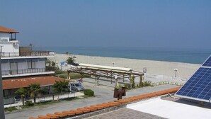 A coastal hotel with a beach view, a covered parking area, and a solar panel installation.