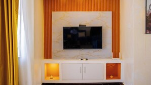 Ein modernes Wohnzimmer mit einem Flachbildfernseher an einer Marmorwand, begleitet von Holzausschlägen und einem weißen Schrank darunter.