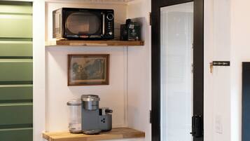 A kitchenette with a microwave, coffee maker, and espresso machine on a wooden countertop.