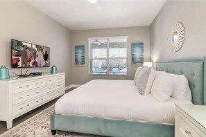A bedroom with a large bed, a dresser, a television, and a window with blinds. - The Minions Mansion 6br Resort Pool Home By Disney (Kissimmee)