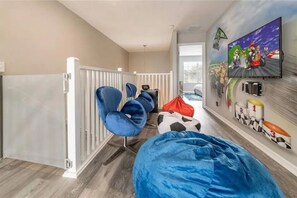 A child's playroom with a large bean bag, blue chairs, a wall mural, and a white radiator. - The Minions Mansion 6br Resort Pool Home By Disney (Kissimmee)