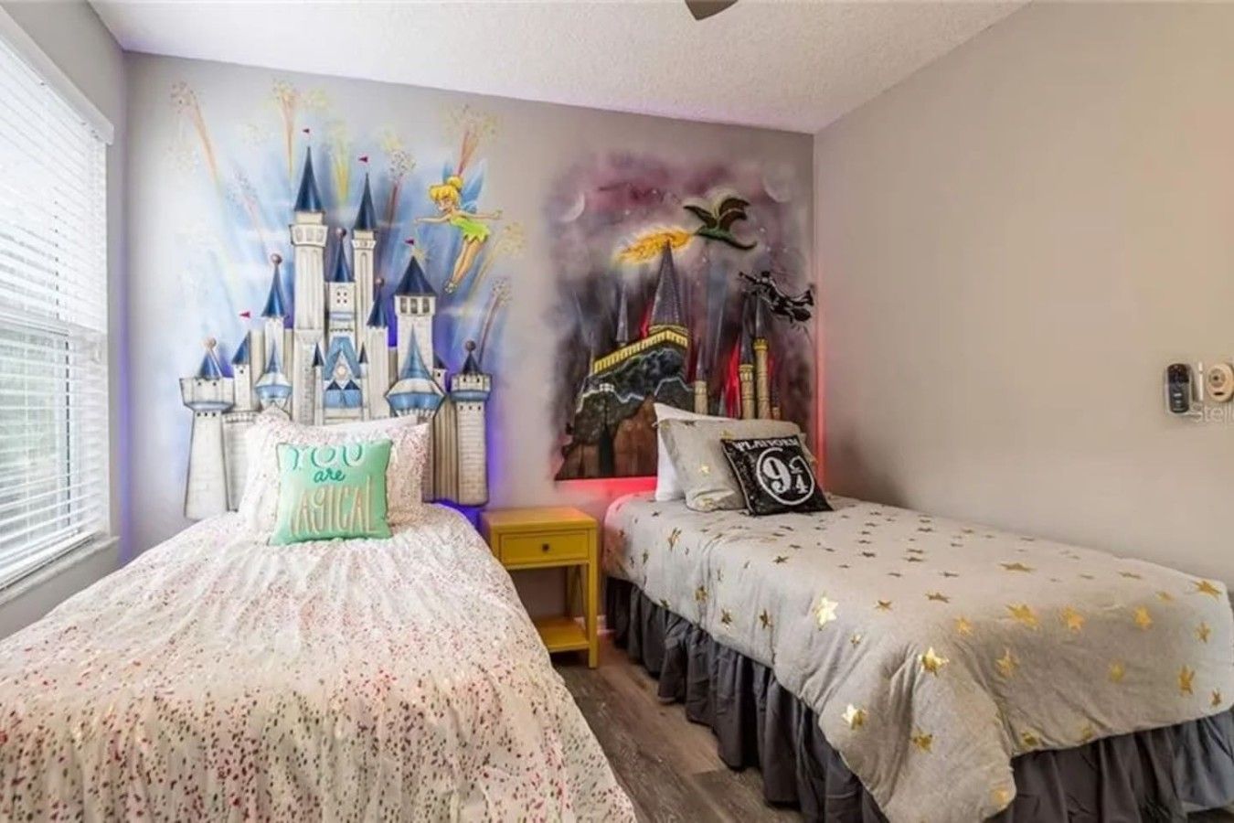A bedroom with two beds, one with a floral bedspread and the other with a star-patterned bedspread.