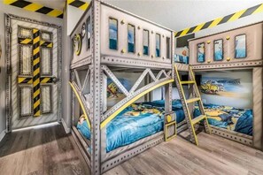 Habitación con literas, una escalera, una puerta con diseño a rayas y un mural en la pared.