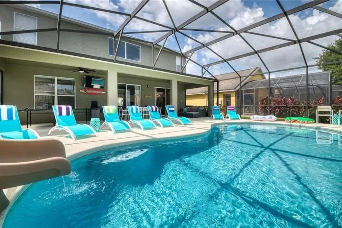 An indoor swimming pool with clear blue water, surrounded by lounge chairs and a covered area with a glass ceiling.
