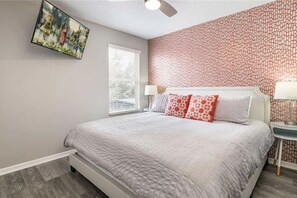 A bedroom with a bed, a window, a ceiling fan, and a wall with a patterned design. - The Minions Mansion 6br Resort Pool Home By Disney (Kissimmee)