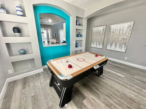 A room with a foosball table, a mirror, shelves with decorative items, and artwork on the walls. - The Minions Mansion 6br Resort Pool Home By Disney (Kissimmee)