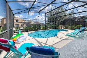 A covered outdoor swimming pool with lounge chairs and inflatable loungers. - The Minions Mansion 6br Resort Pool Home By Disney (Kissimmee)